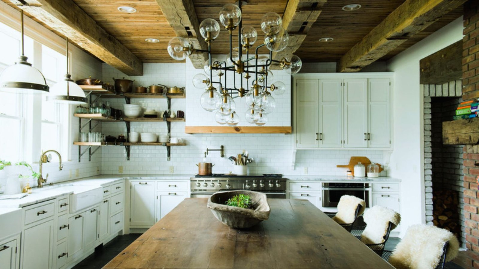 Rustic kitchen with wooden beams, a large island, and white cabinets. A modern chandelier hangs above. Cozy, inviting atmosphere with a warm tone.</p>
<p>Wooden ceiling beams are one of the most recognized features of this style.</p>
<p>They add height, warmth, and a rustic structure to the space. Dark or honey-toned wood works best. Pair them with white plaster walls for contrast.</p>
<h3>2. Terracotta Tile Flooring Italian Villa Kitchen</h3>
<p><img decoding=