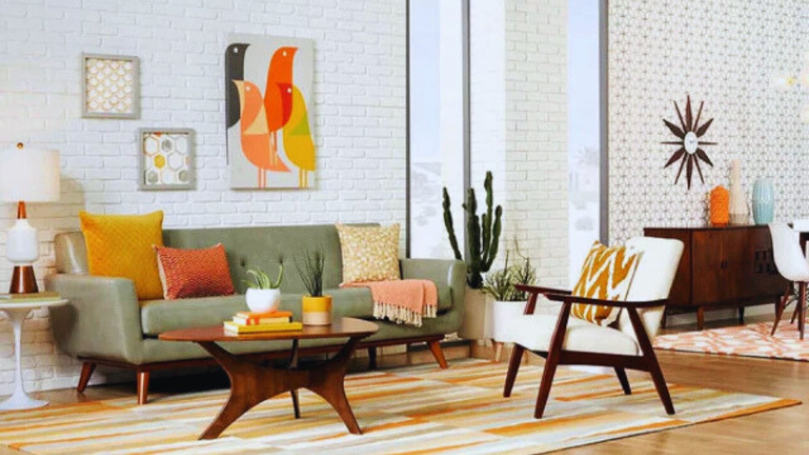 Mid-century modern living room with a green sofa, orange and yellow cushions, a patterned rug, art on a white brick wall, and a sunburst clock.