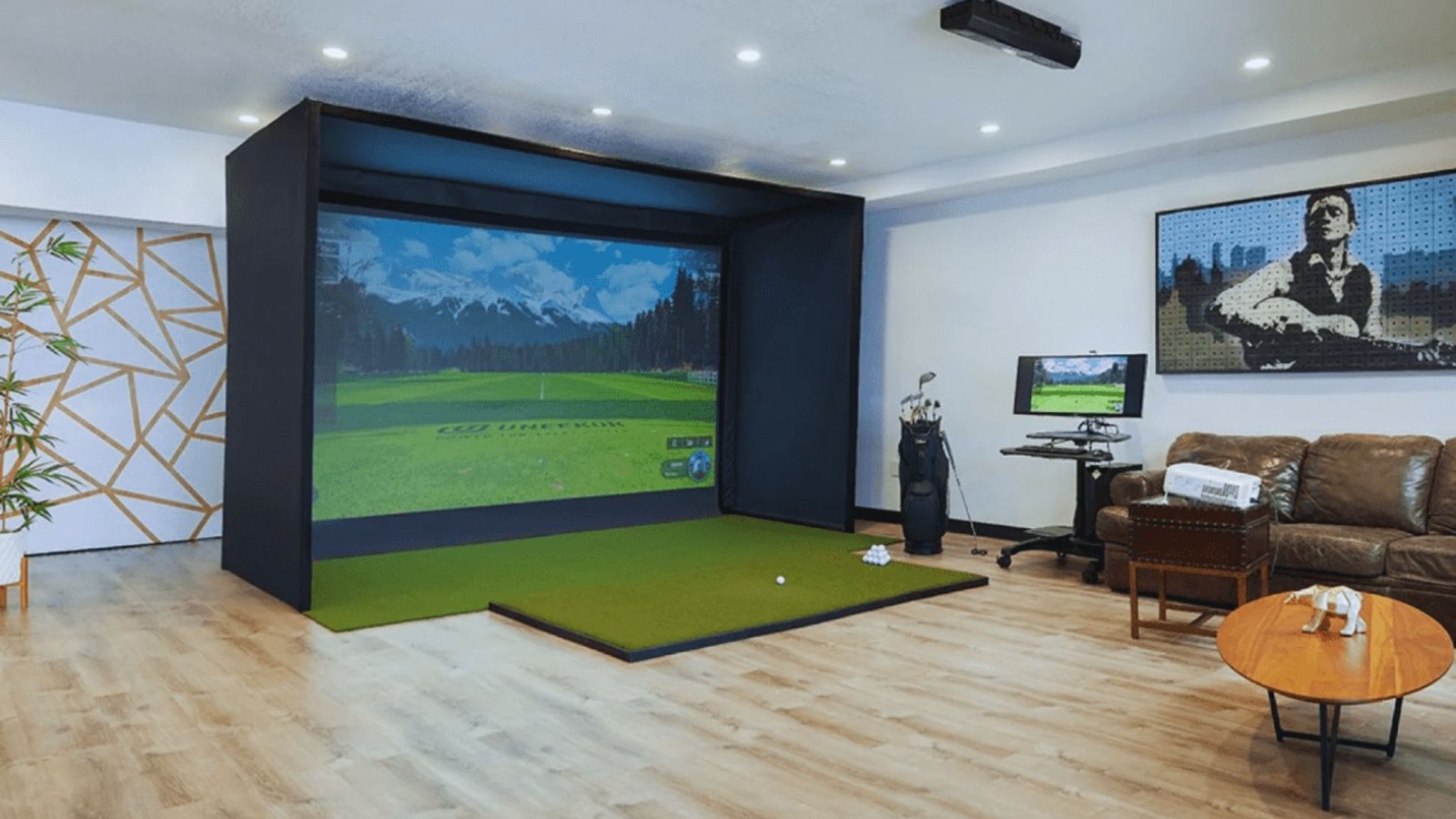 A modern home golf simulator setup with a virtual green and projected mountains. Cozy seating area with a leather couch and guitar artwork on the wall.