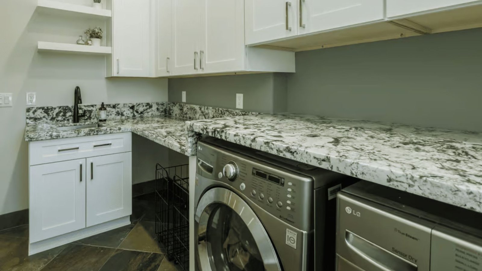 A tidy laundry room featuring sleek granite countertops and organized appliances.
