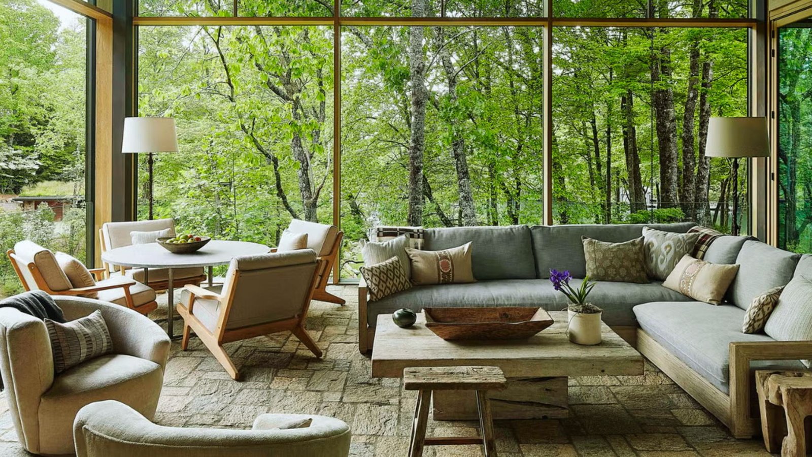 A cozy living room featuring a large window that offers a view of the serene woods outside.