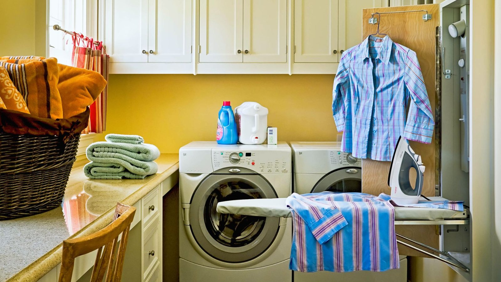  A laundry room featuring a washer and dryer, with shelves and laundry supplies visible in the background.