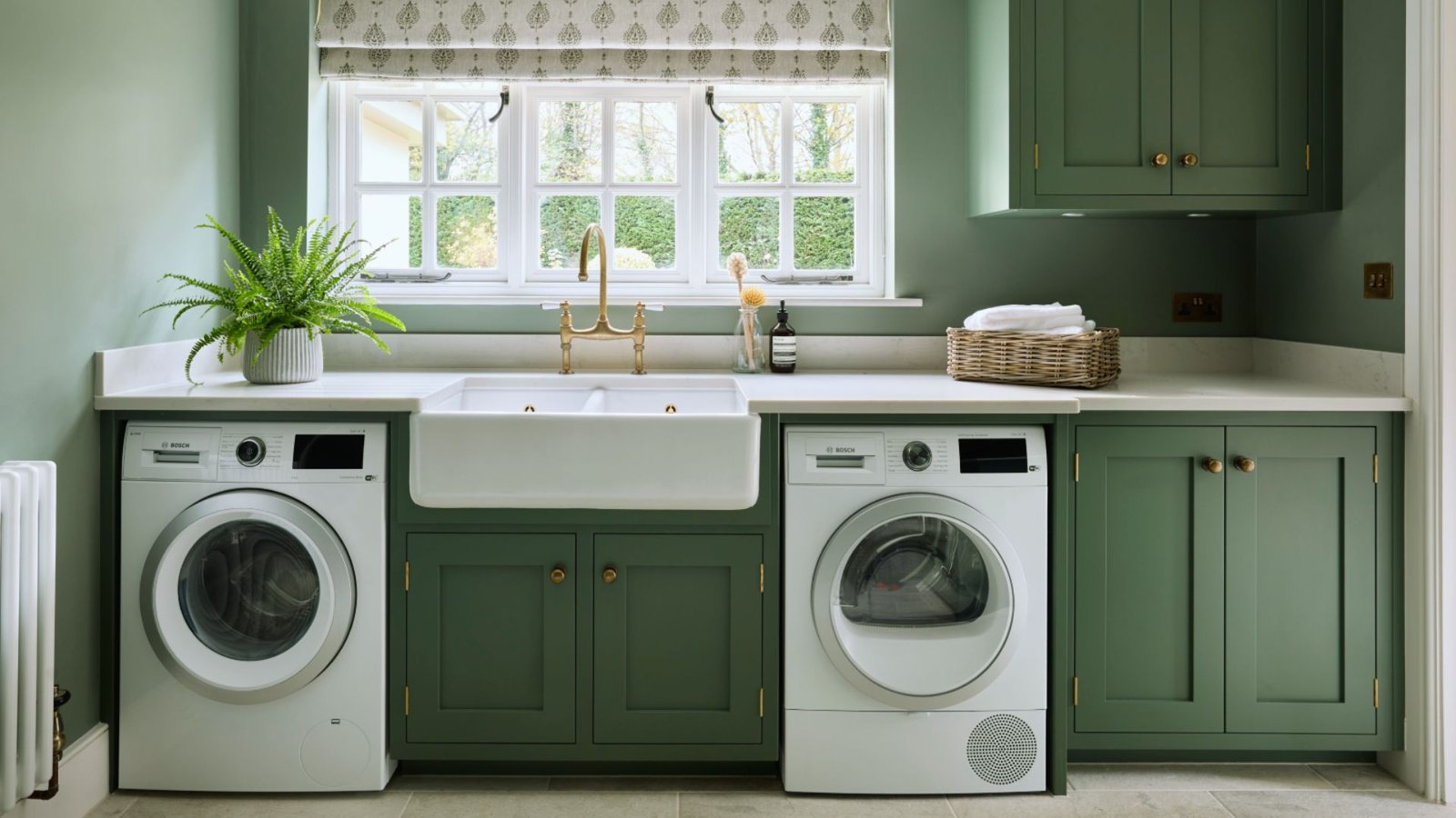 . A green laundry room featuring a washer and dryer, with bright walls and organized space for laundry tasks.