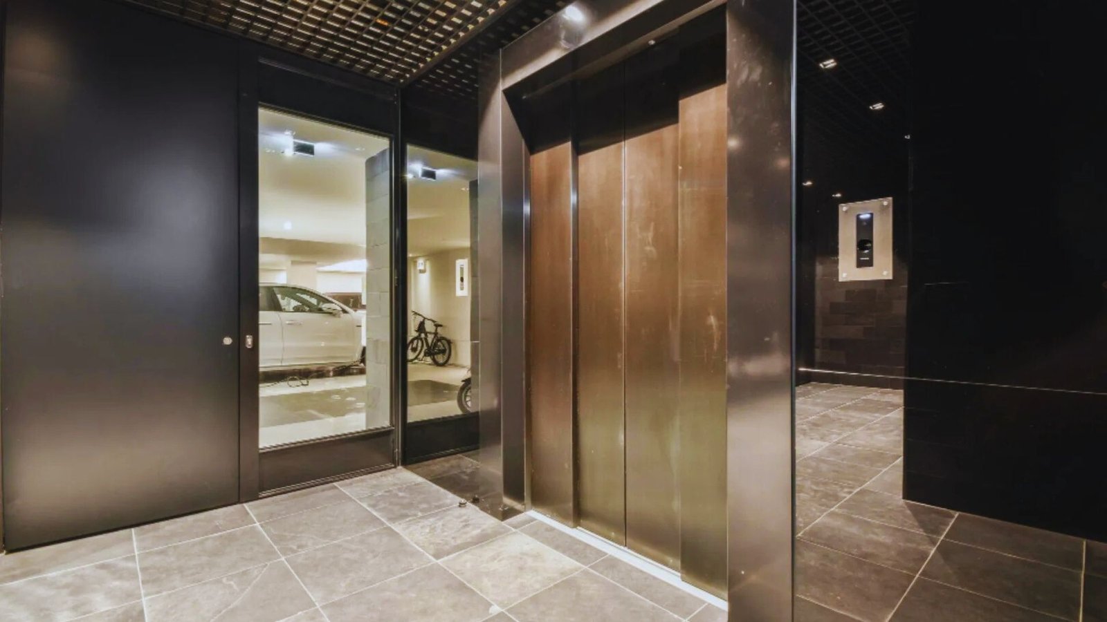 A stylish elevator showcasing a glass door and a minimalist black wall design.