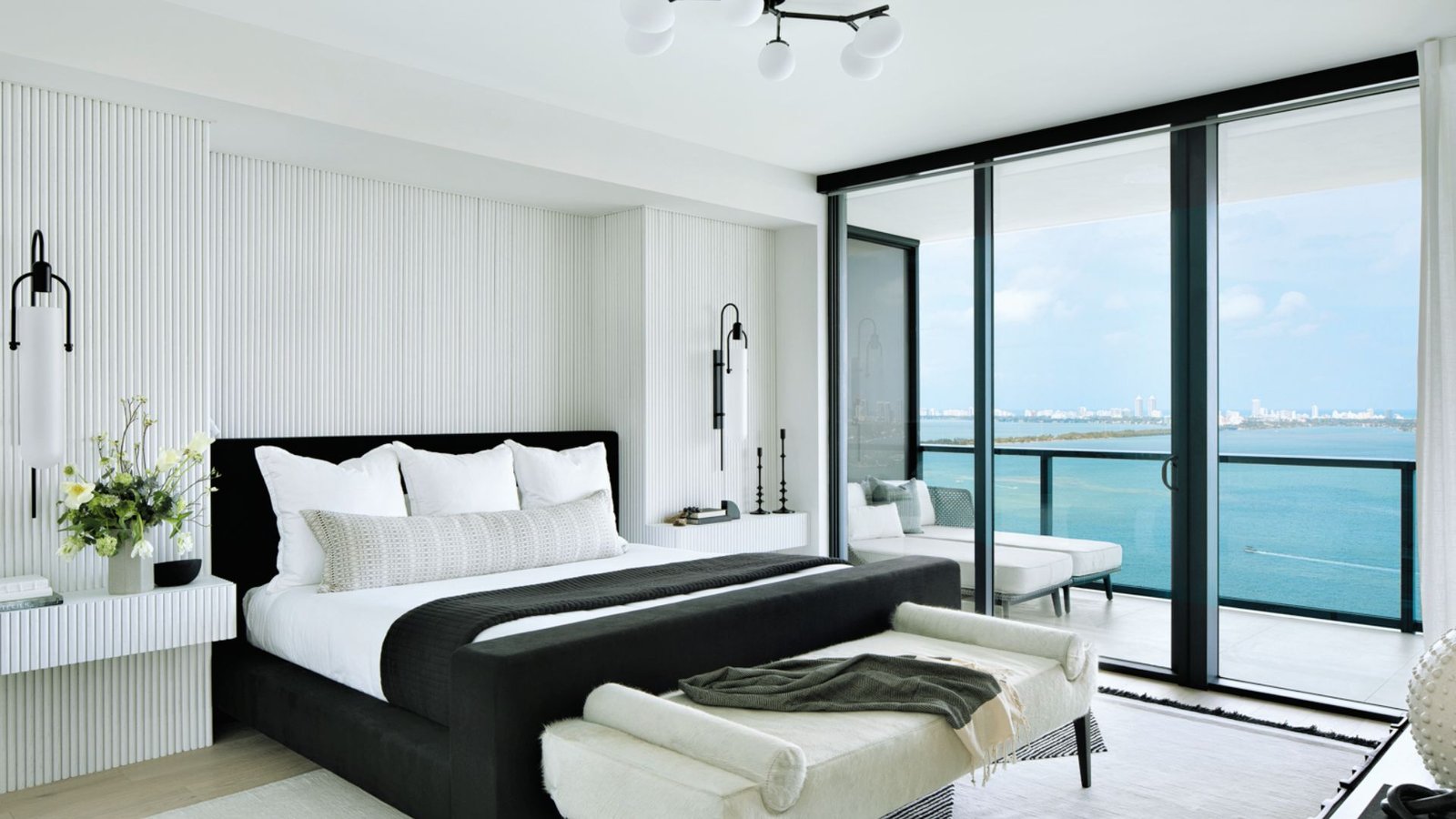 A serene bedroom featuring a bed and a large window showcasing a stunning ocean view.