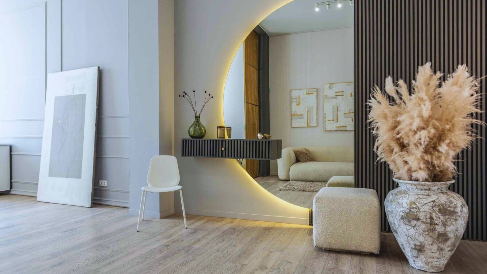 A modern living room featuring a round mirror above a stylish vase on a table, creating a chic and inviting atmosphere.