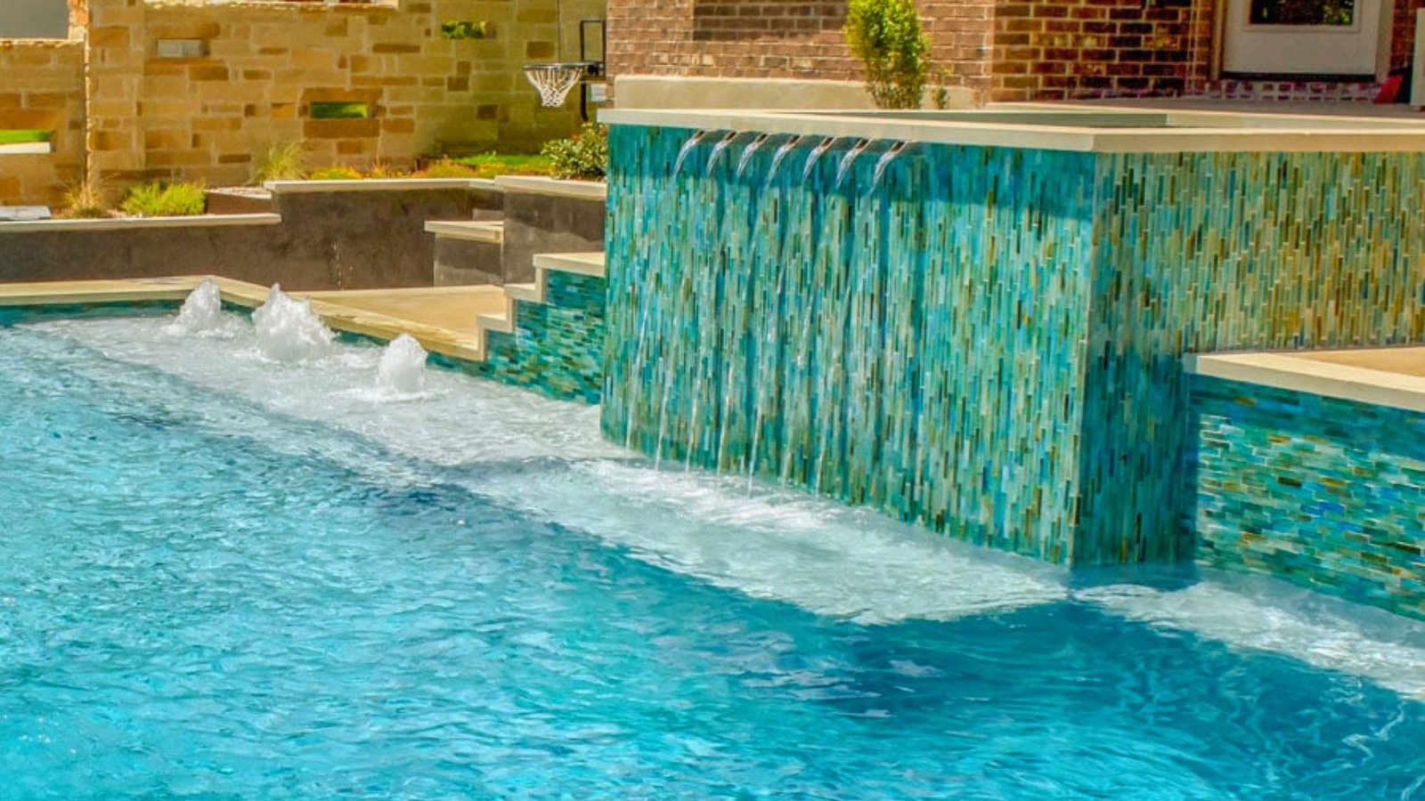 A serene pool featuring a cascading waterfall and an elegant fountain, surrounded by lush greenery.