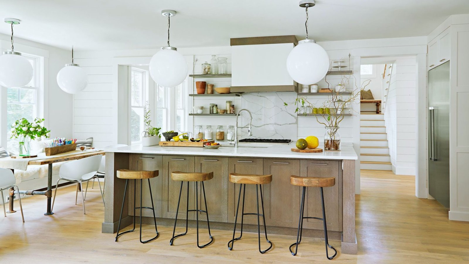 A modern kitchen featuring a central island with stools arranged around it for casual dining and socializing.