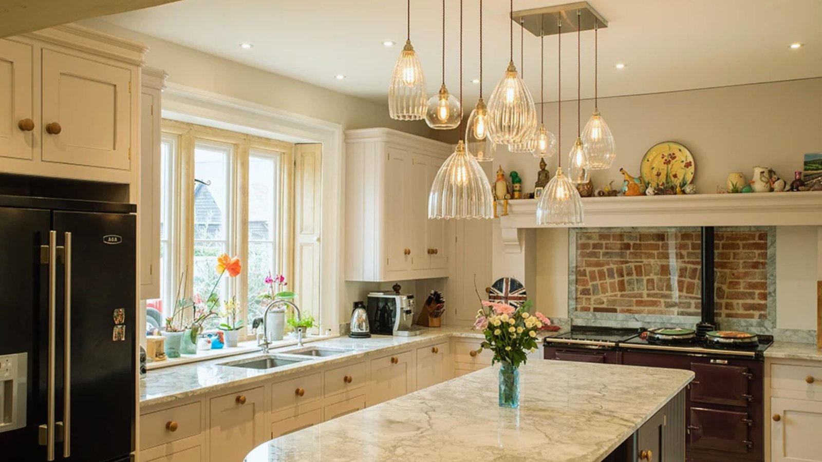 A modern kitchen featuring a marble island and elegant pendant lights hanging above.
