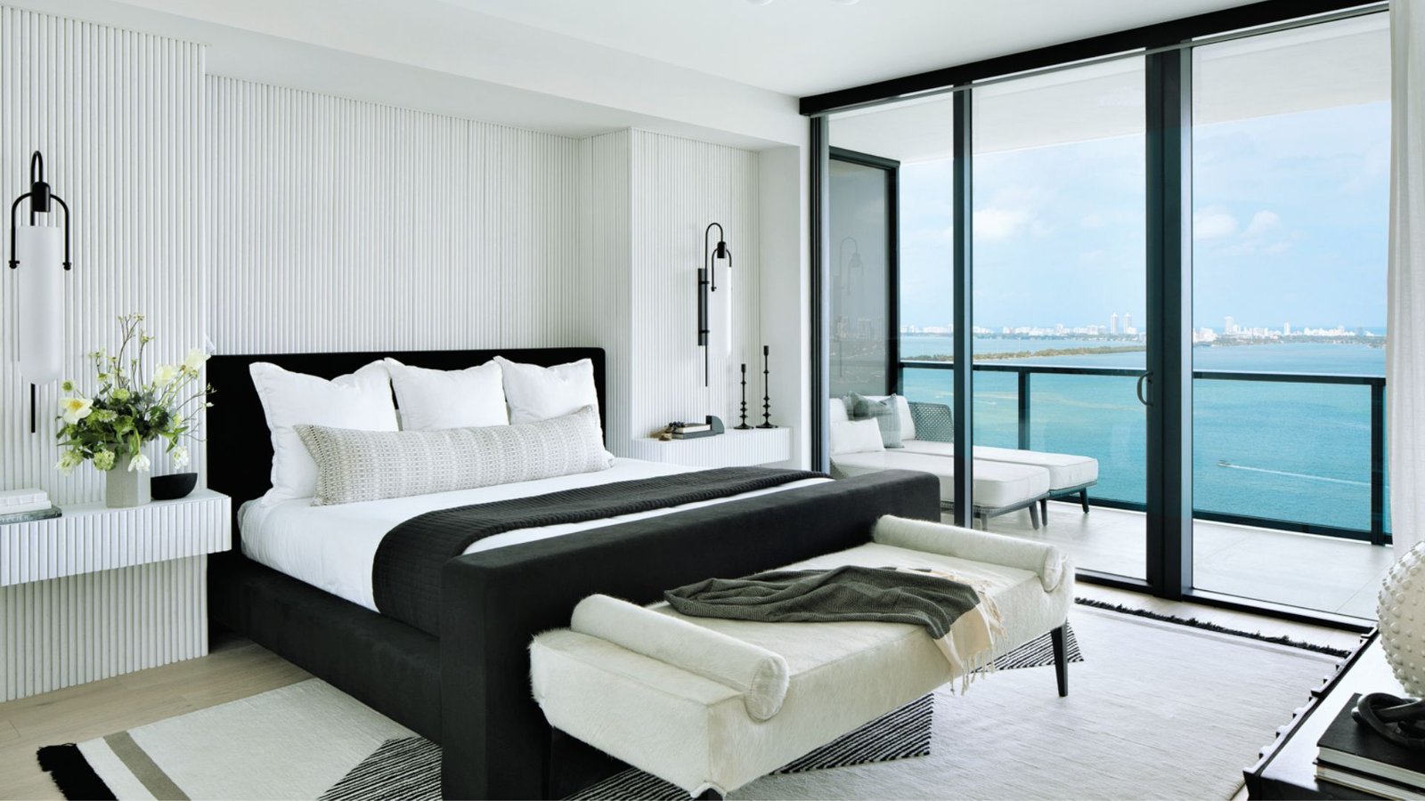 A serene bedroom featuring a bed and a large window showcasing a beautiful ocean view.