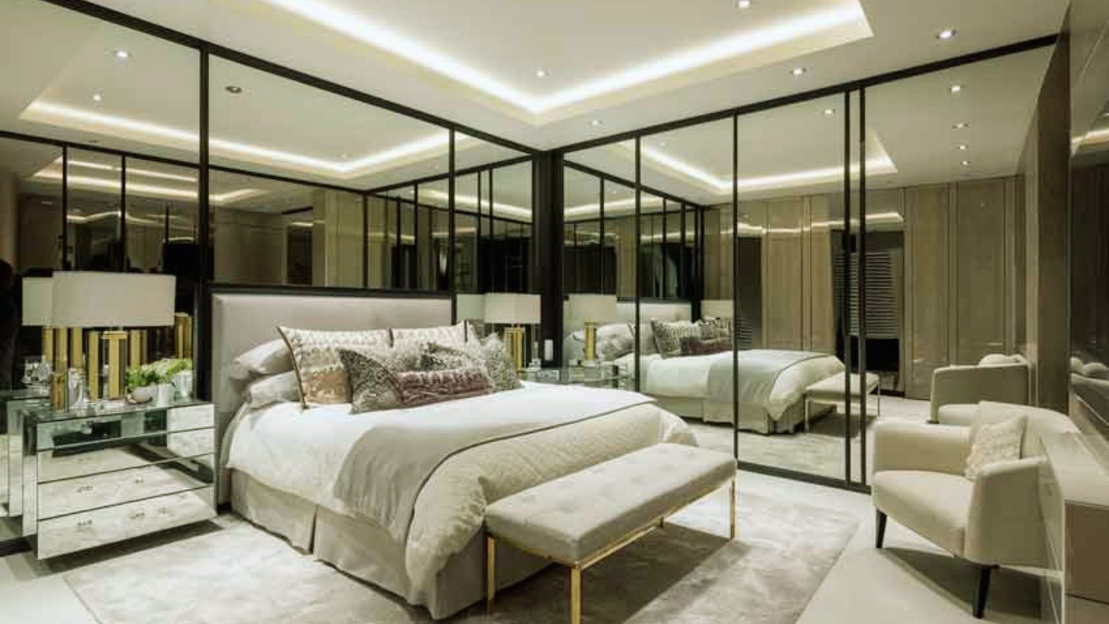 A modern bedroom showcasing mirrored walls and a comfortable bed, reflecting light and adding depth to the space.