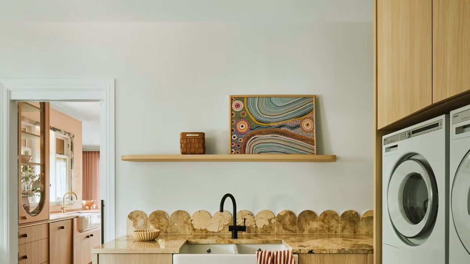 A laundry room featuring a sink and a washing machine, with clean, organized space for laundry tasks.