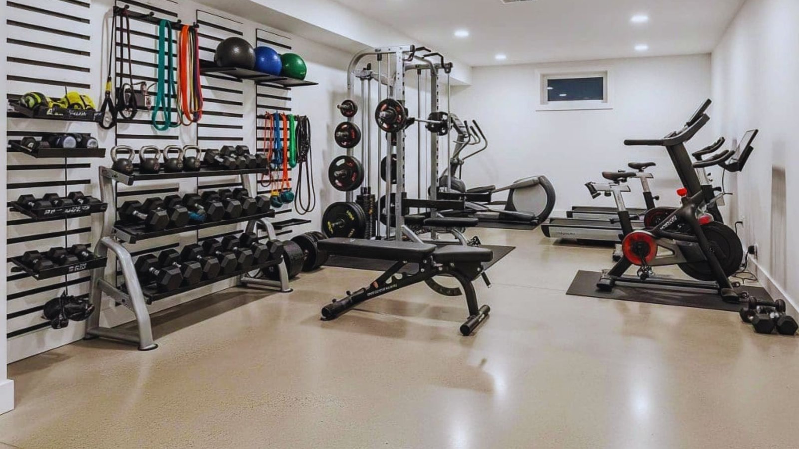 A home gym featuring various fitness equipment, including weights, a treadmill, and exercise mats.