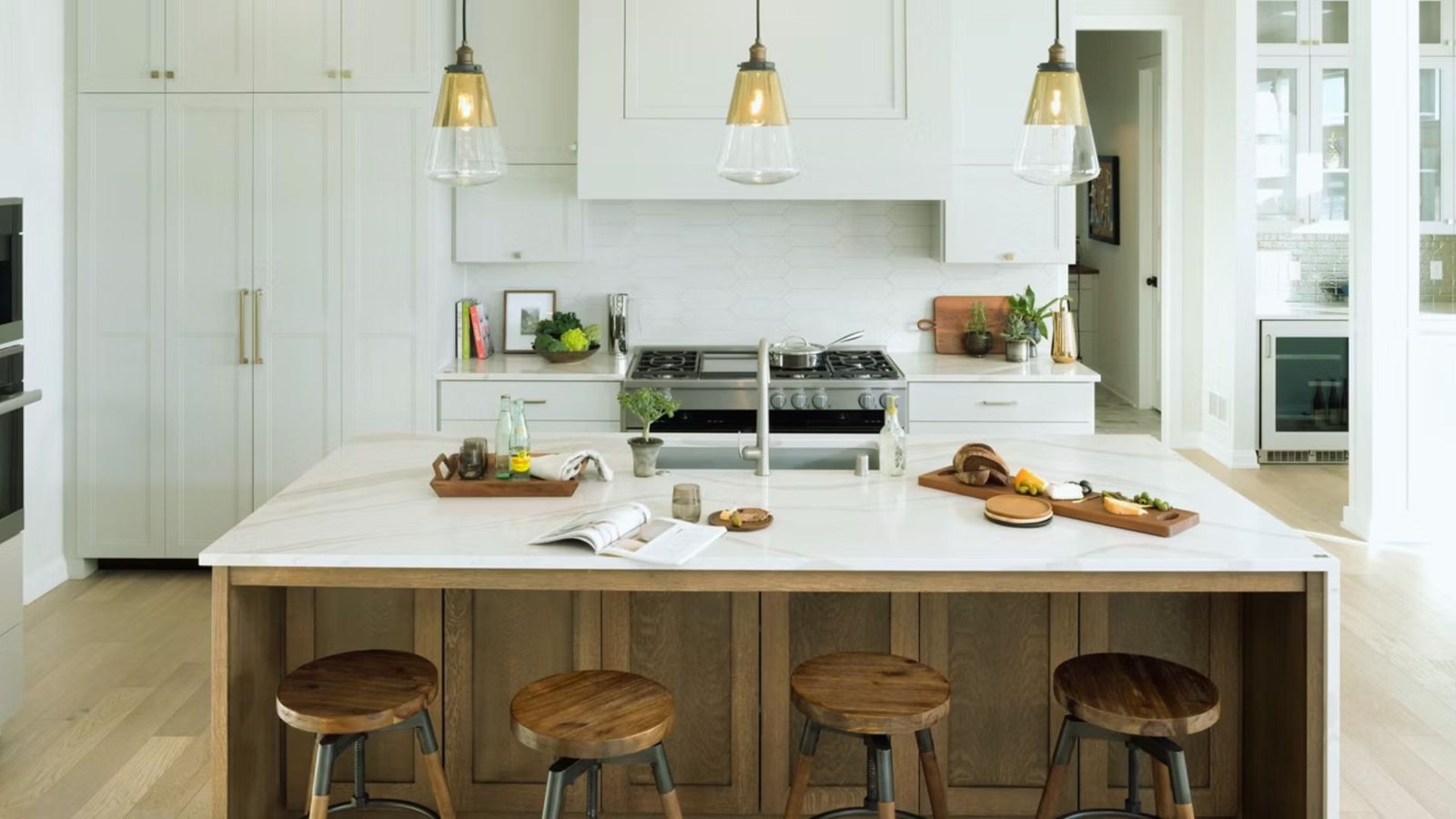 A modern kitchen featuring white cabinets and wooden stools arranged around a central island.