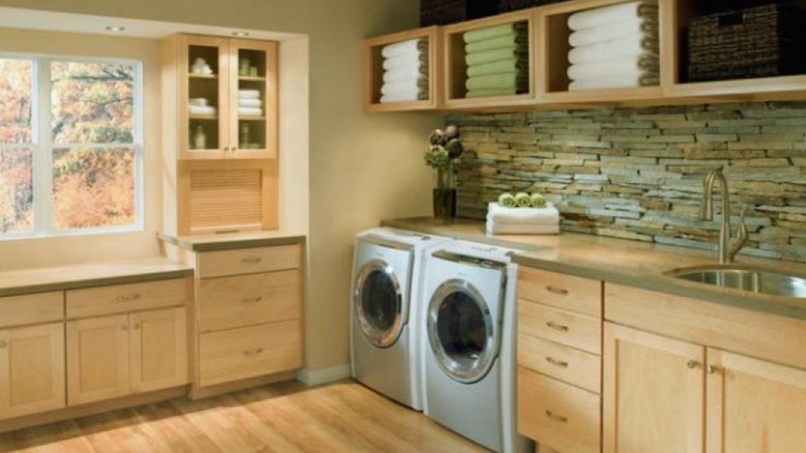 A tidy laundry room featuring a washer and dryer, with organized shelves and bright lighting.
