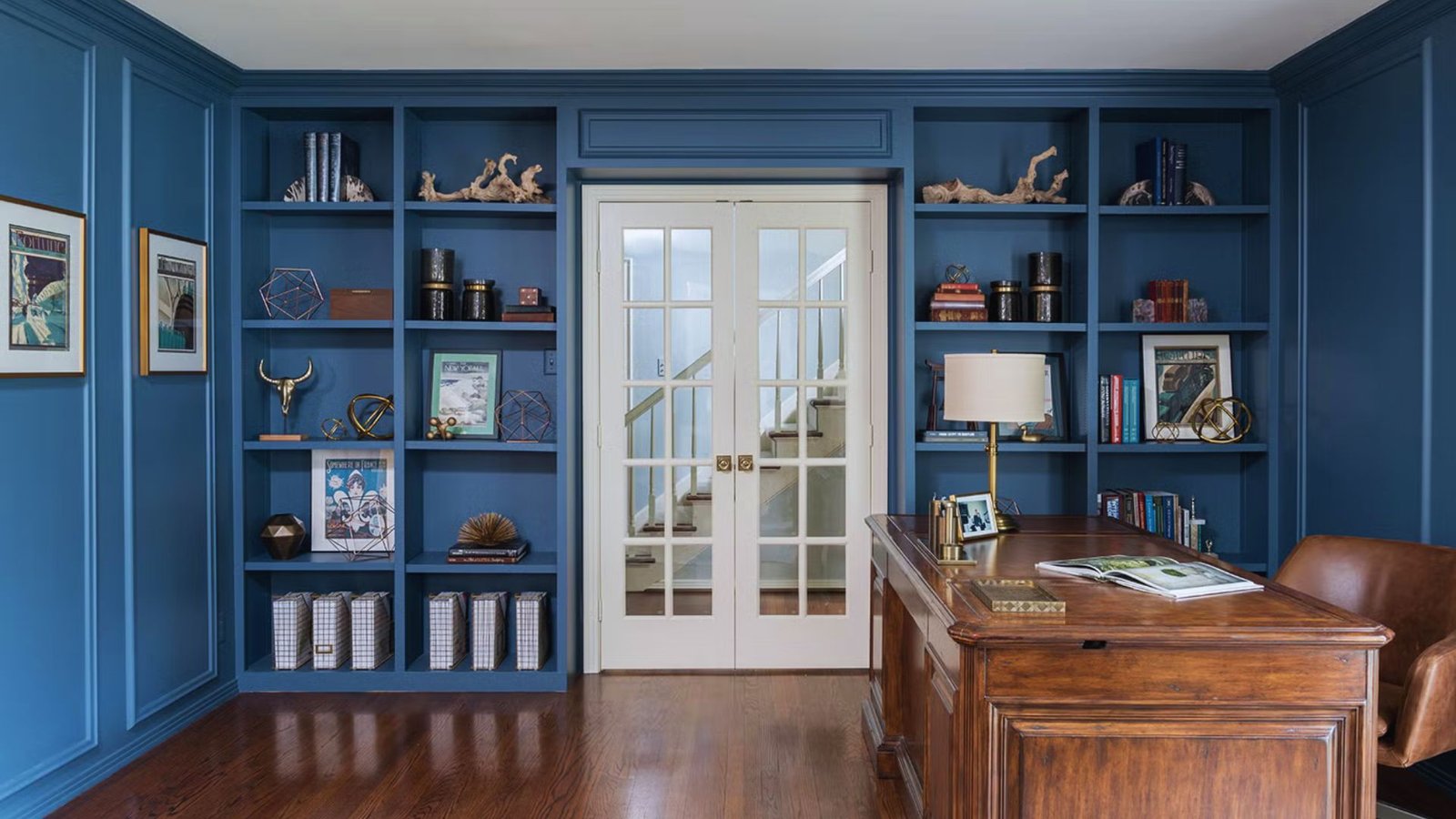 A home office featuring blue walls and wooden floors, creating a calm and inviting workspace atmosphere.