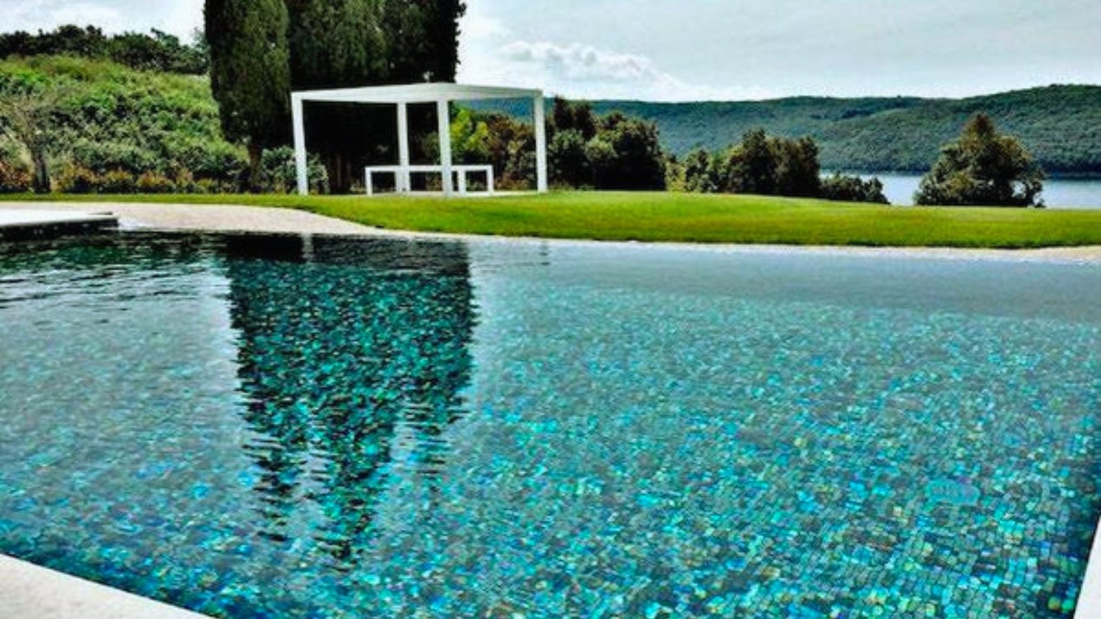 A serene pool with clear blue water, shaded by a large white umbrella, inviting relaxation on a sunny day.
