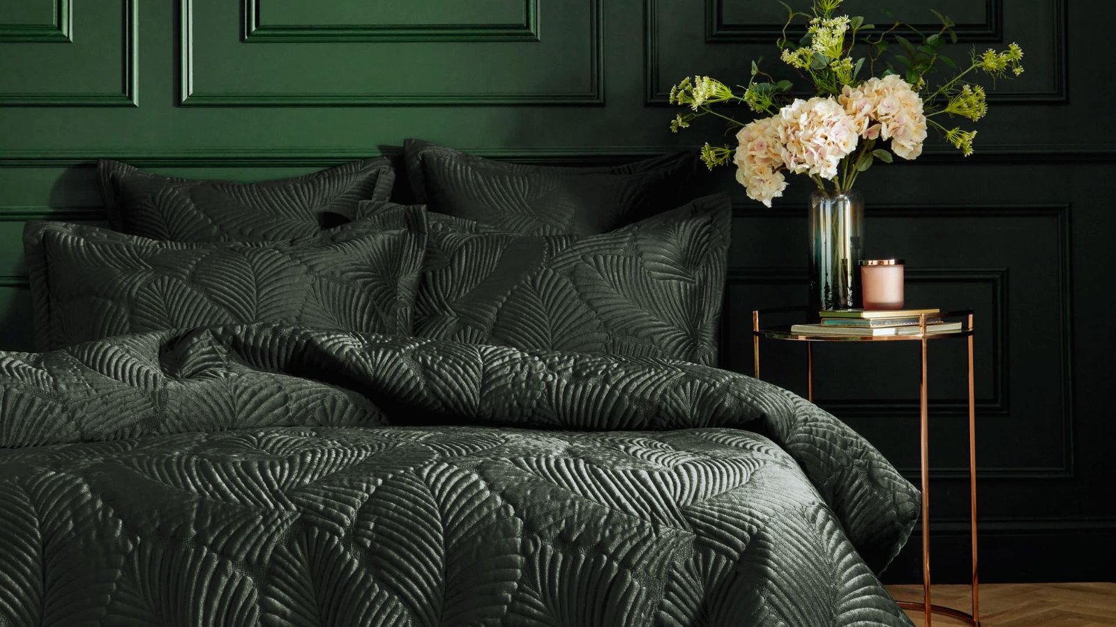 A bed featuring a black comforter, positioned in a room with green walls, exuding a contemporary and relaxing vibe.