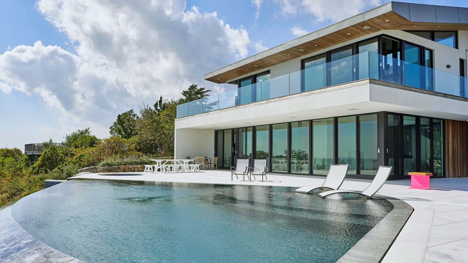 A contemporary home featuring a swimming pool and an expansive deck for outdoor relaxation and entertainment.