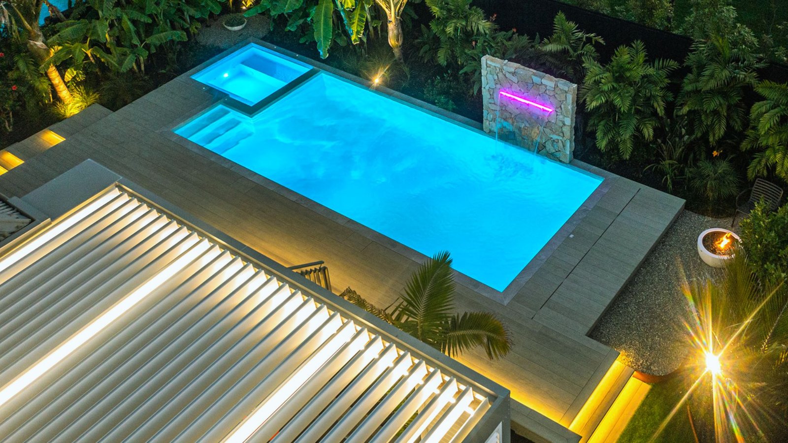 A brightly lit pool surrounded by a cozy lounge area, creating a relaxing evening atmosphere.