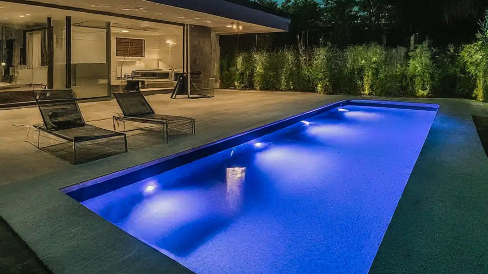 A modern swimming pool illuminated with vibrant blue lights, creating a serene and inviting atmosphere.
