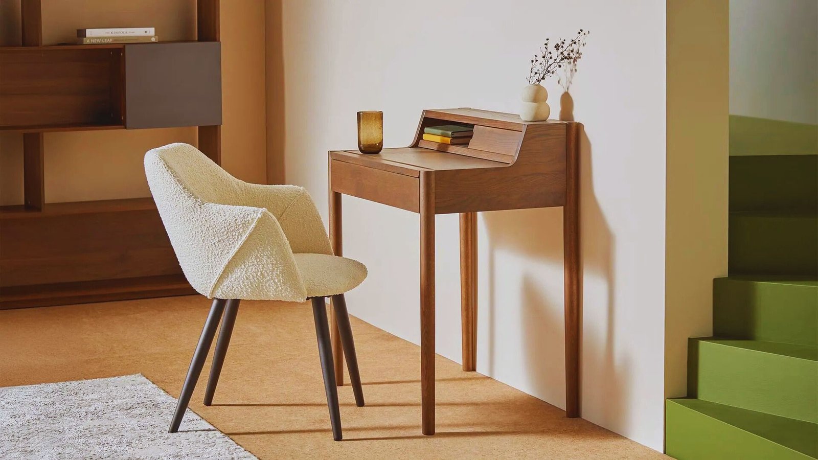 A small desk with a chair beside it and a shelf above, creating a compact workspace.