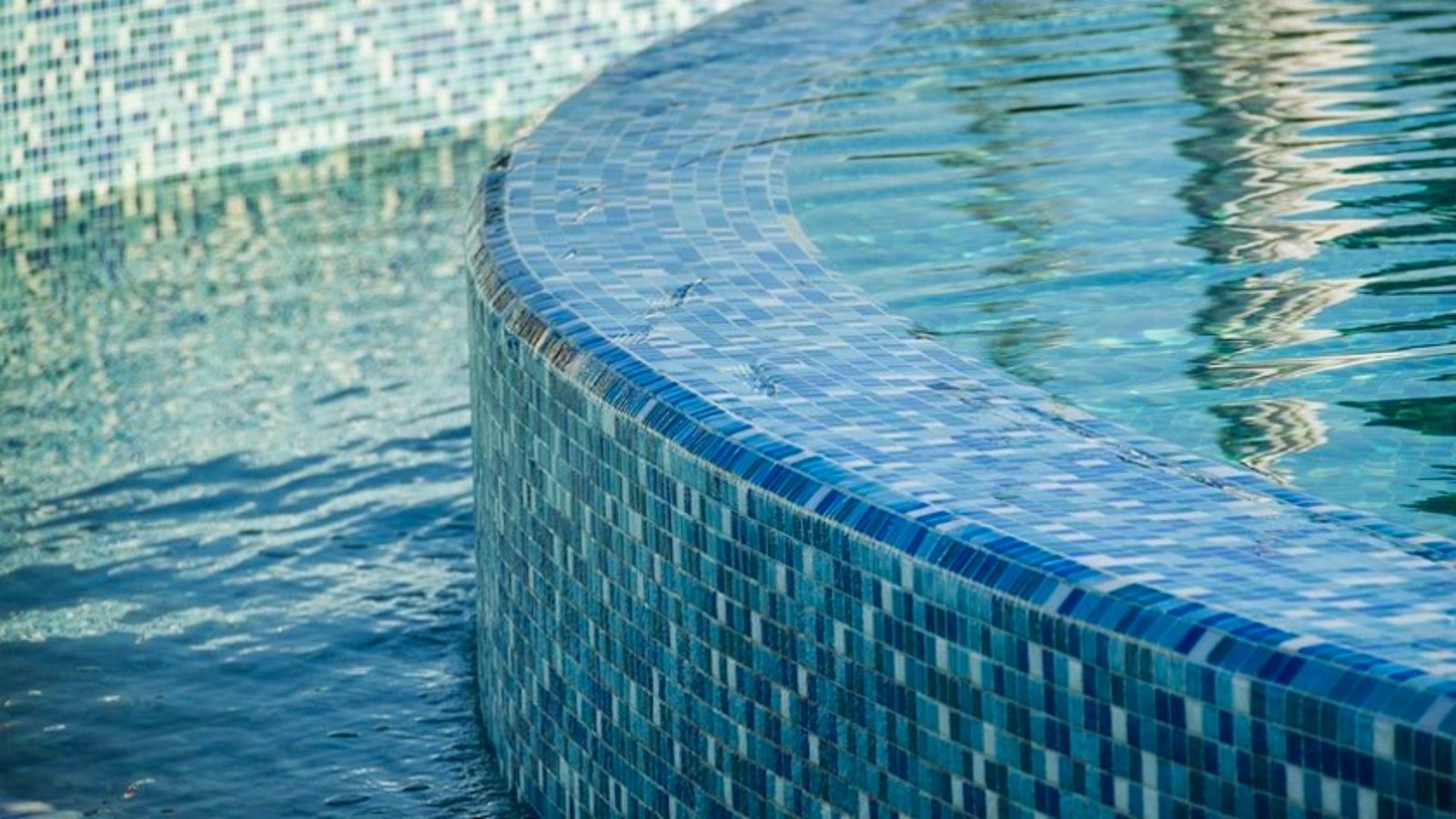 A blue mosaic tile pool surrounded by a matching blue wall, creating a serene and cohesive aquatic environment.