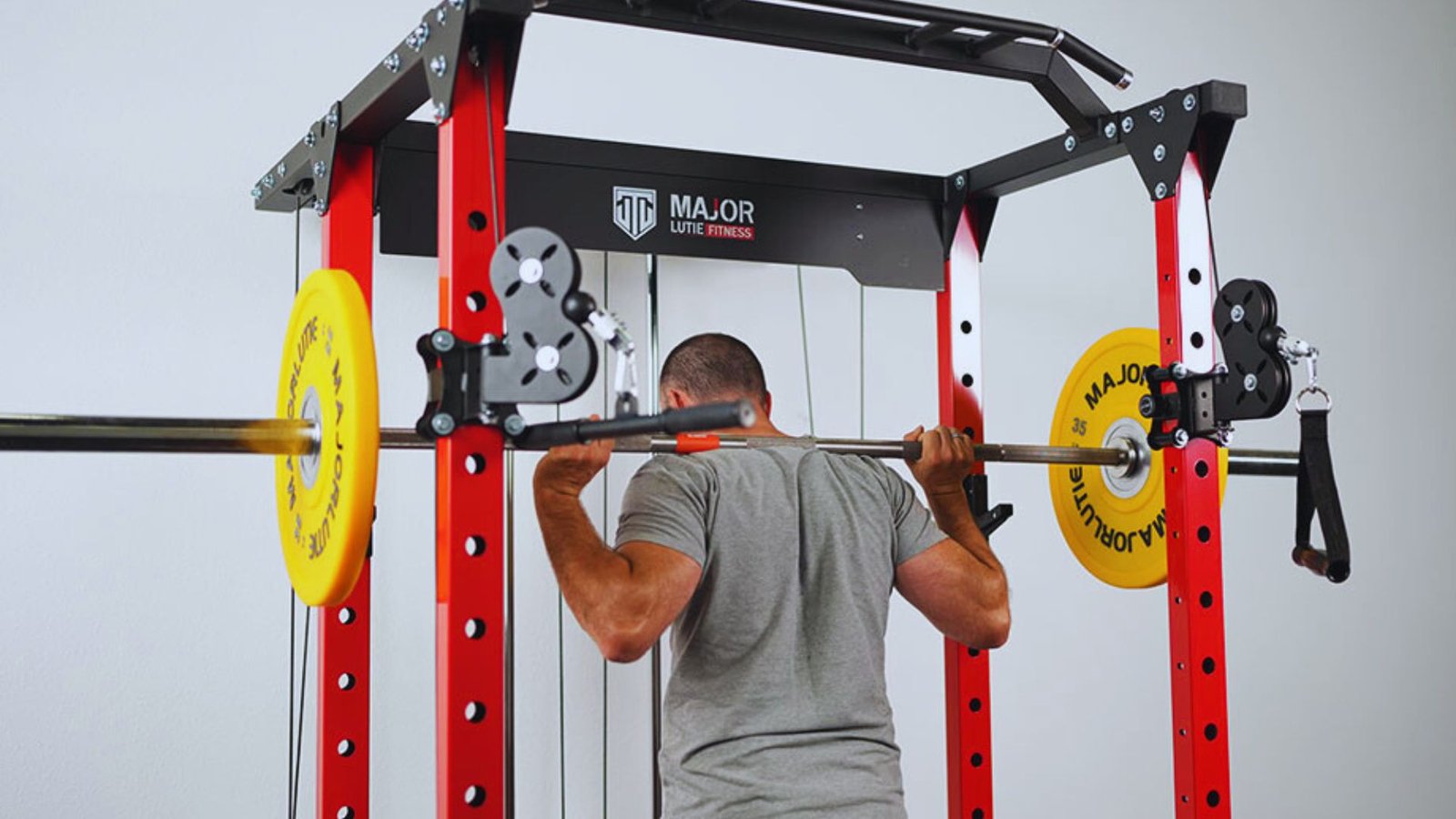 A man performs a squat with weights in a squat rack, showcasing his workout routine in a gym.