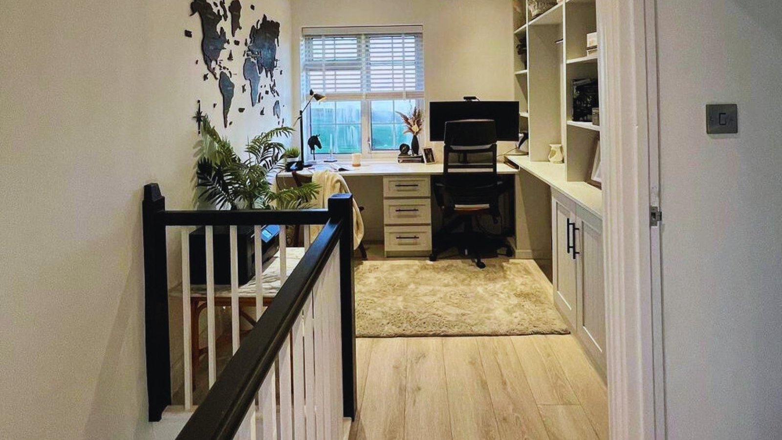 A hallway featuring a desk with a computer, providing a workspace in a narrow corridor.