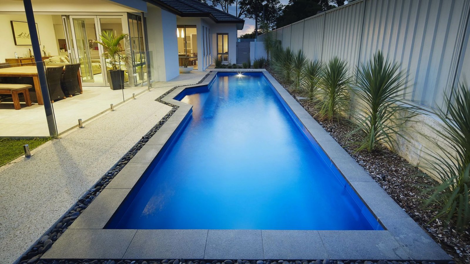 A blue swimming pool surrounded by a grassy backyard, inviting for relaxation and leisure activities.