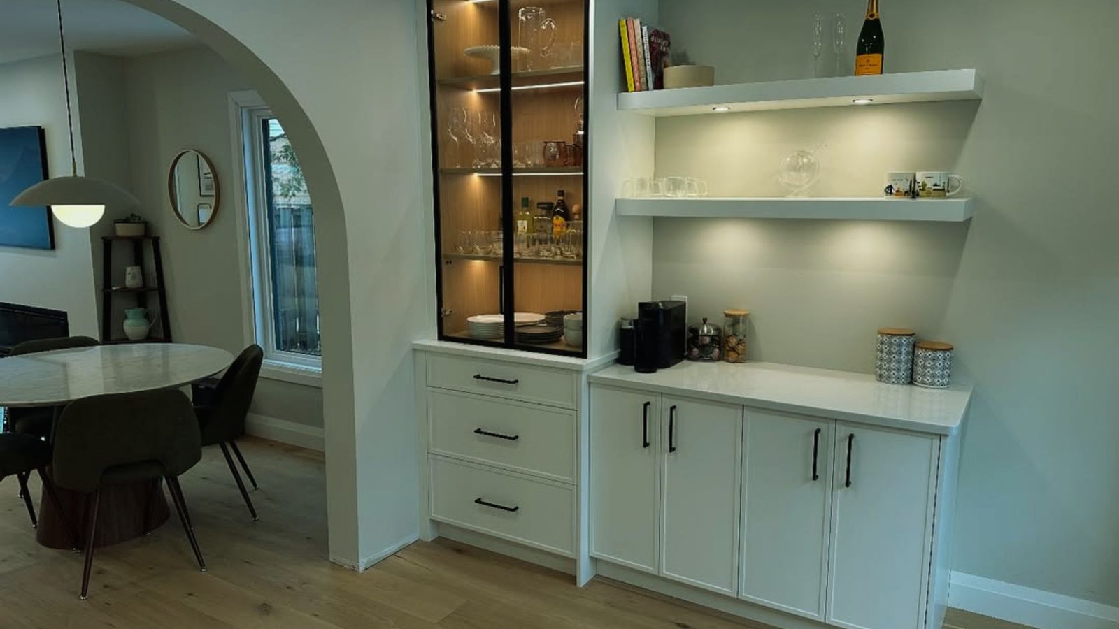 Bright kitchen with sleek white cabinets and a cozy dining table in the center.