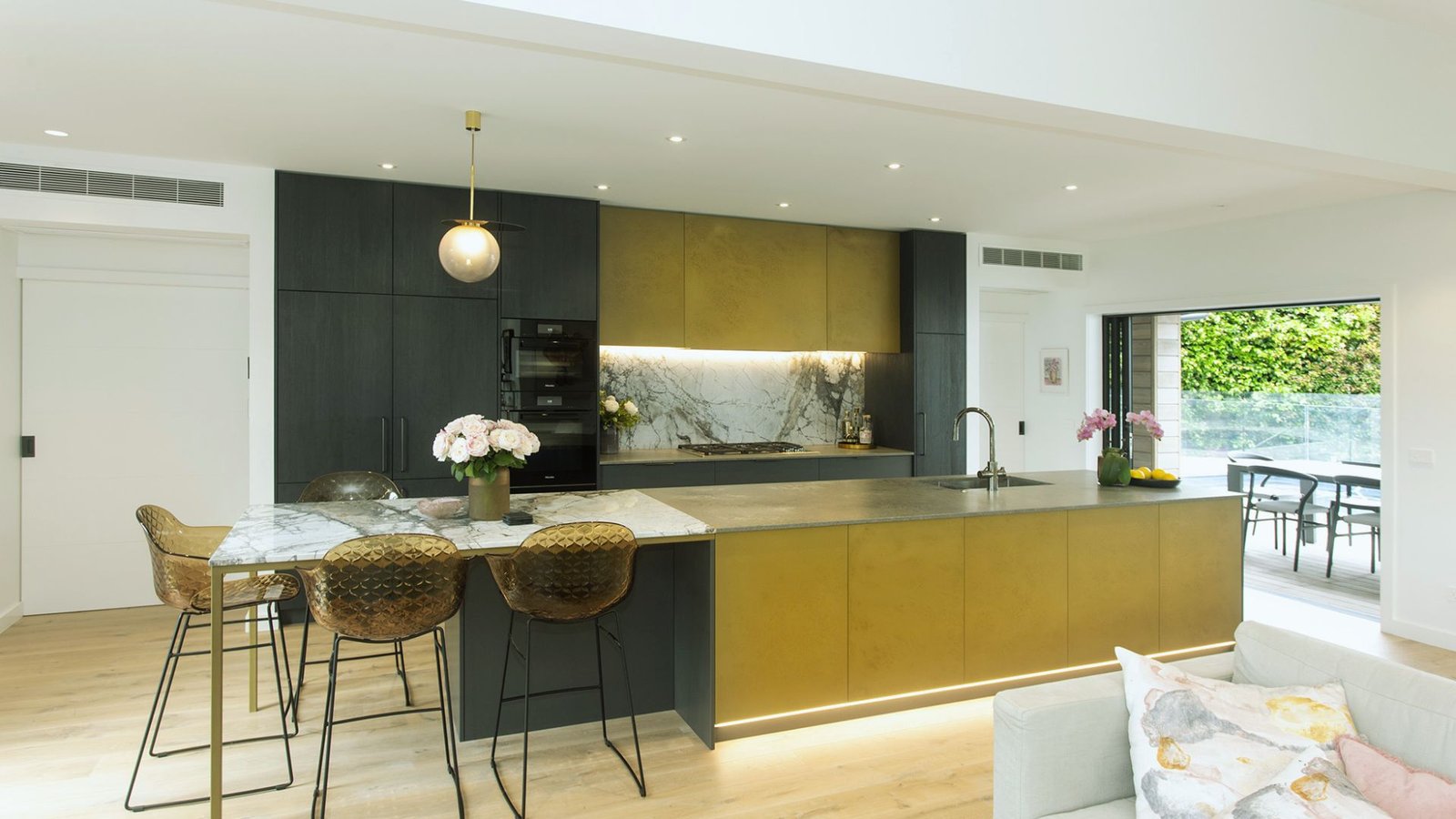 A sleek modern kitchen featuring a gold and black island, showcasing contemporary design and elegant finishes.