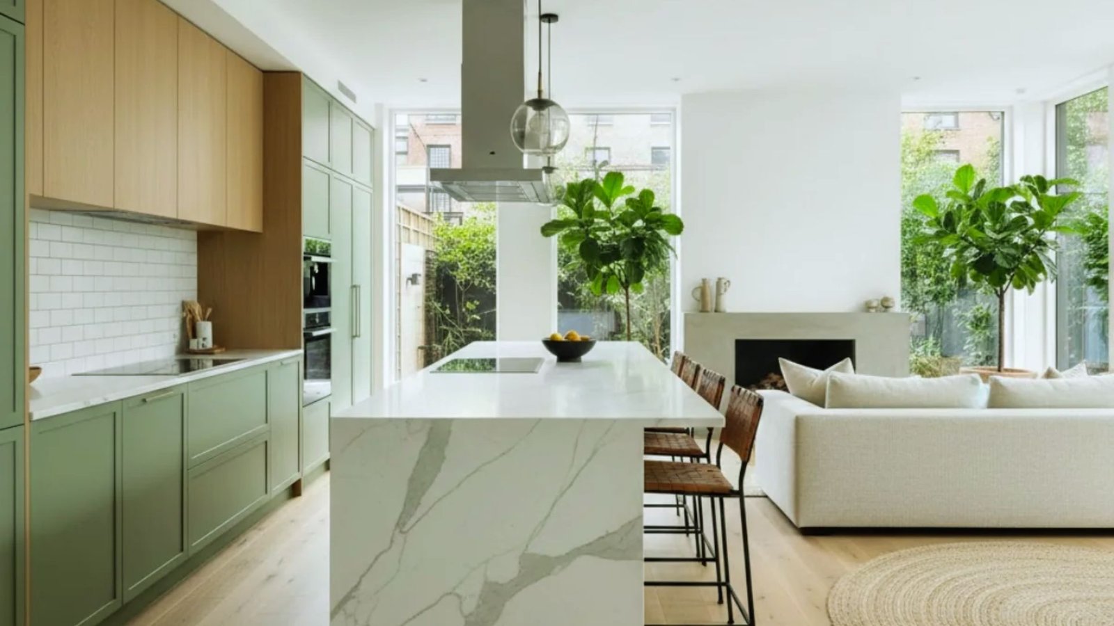 A modern kitchen featuring green cabinets and a sleek white marble island, showcasing contemporary design elements.