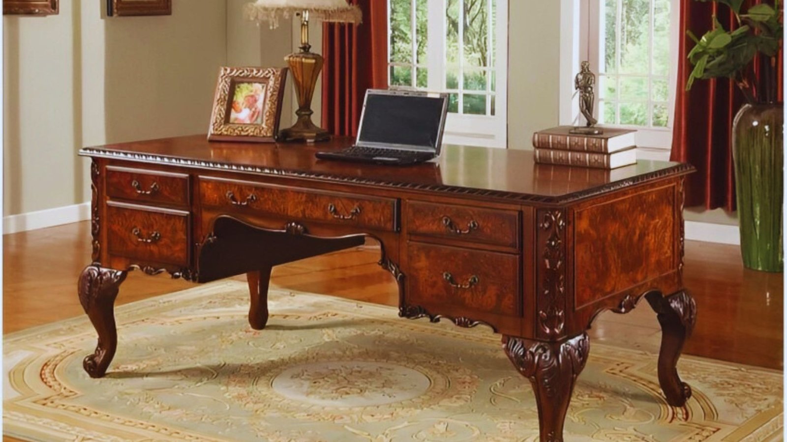 A wooden desk with a laptop open on top, surrounded by a few stationery items.