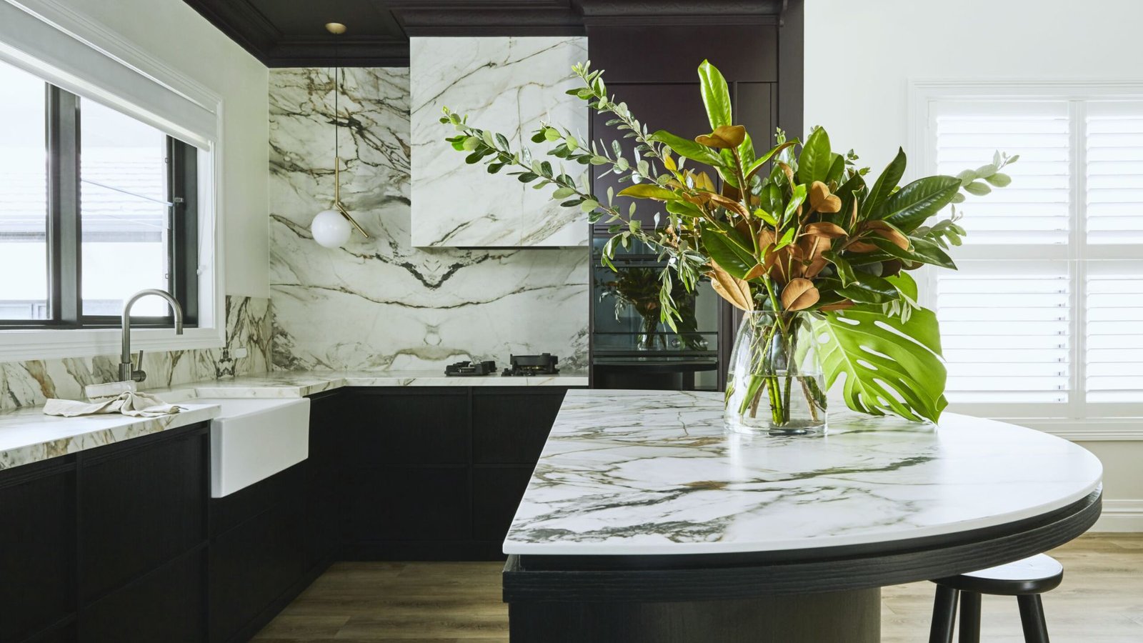 A modern kitchen featuring elegant marble countertops and sleek black cabinets.