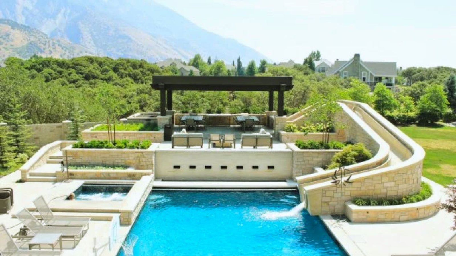 A swimming pool featuring a slide, surrounded by a spacious patio area for relaxation and leisure activities.