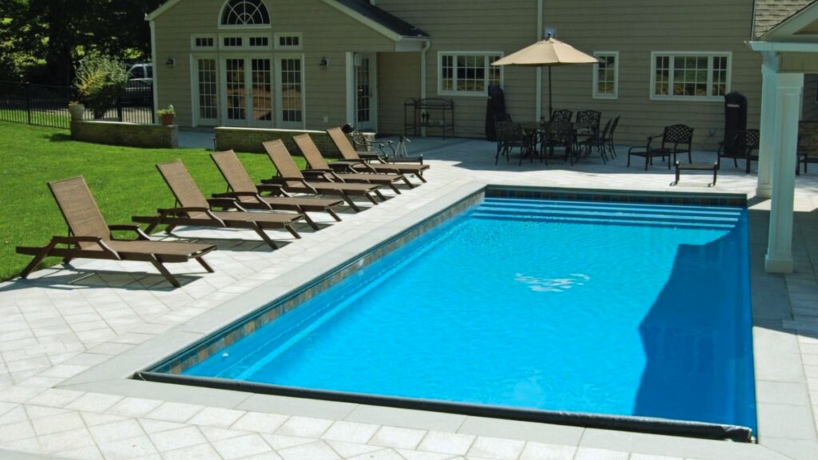 A swimming pool surrounded by a patio and several chairs for relaxation.