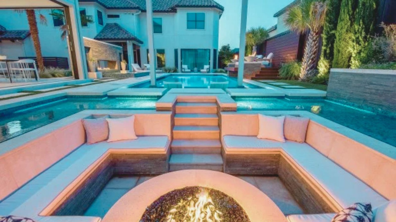 A serene pool surrounded by a fire pit and comfortable seating area, perfect for relaxation and gatherings.