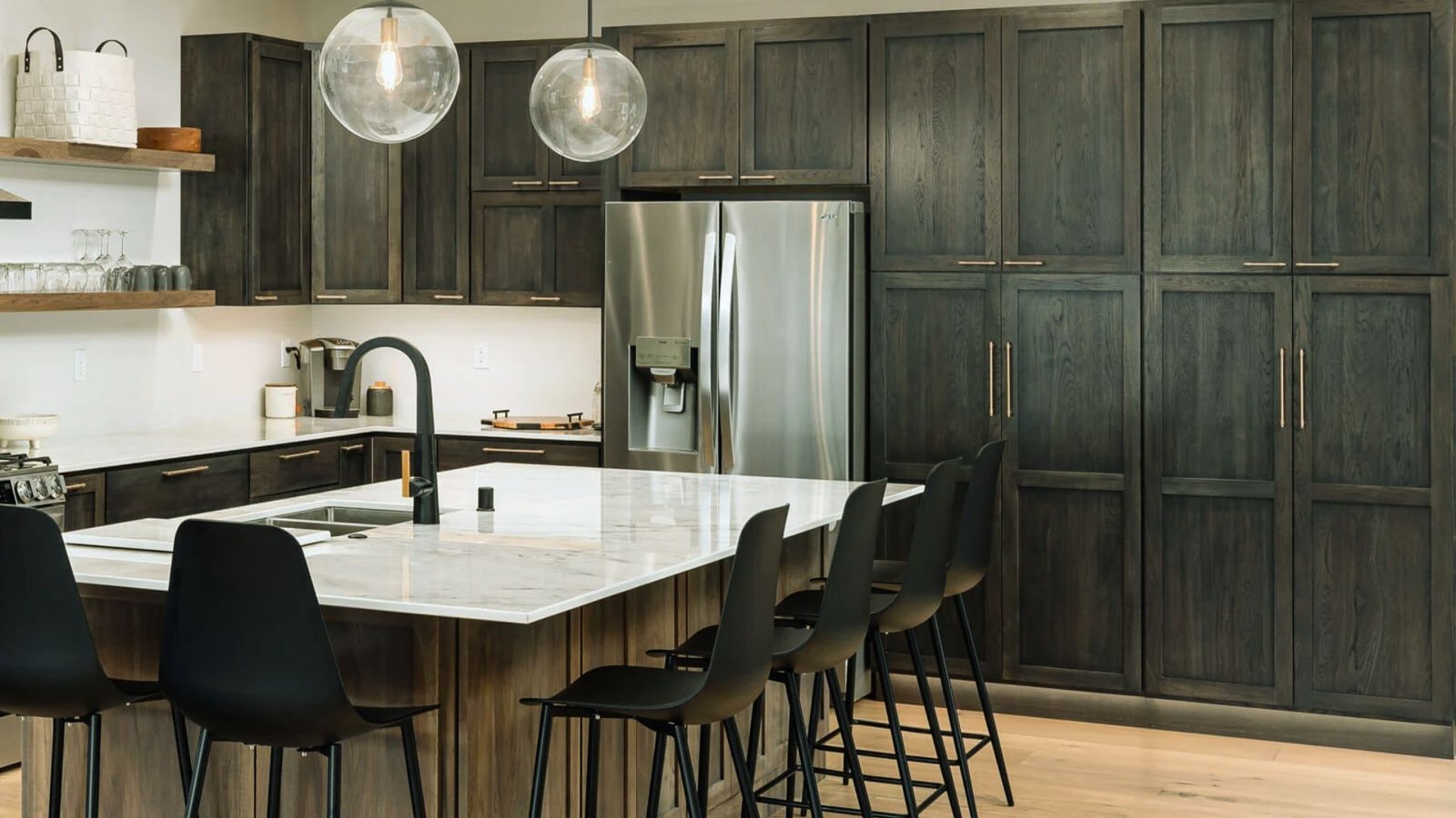 A modern kitchen featuring dark wood cabinets and sleek black chairs arranged around a dining table.