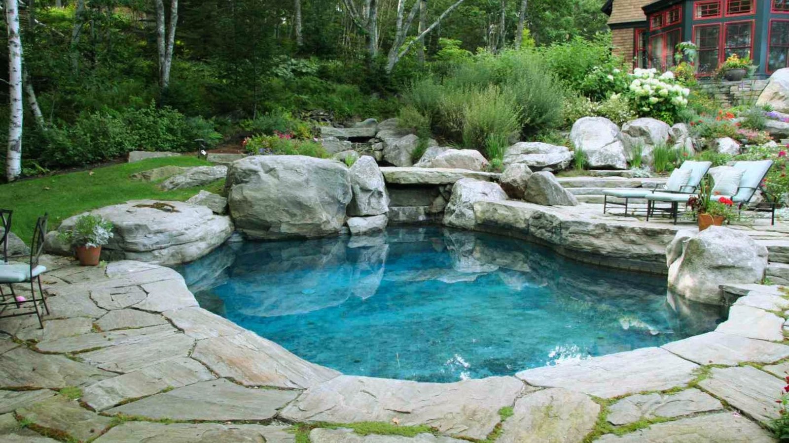 A backyard pool surrounded by natural rocks and a decorative rock wall, creating a serene outdoor space.