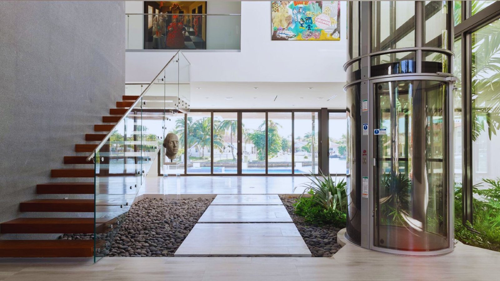 A stylish modern house with large glass walls and a prominent staircase, emphasizing open and airy living spaces.