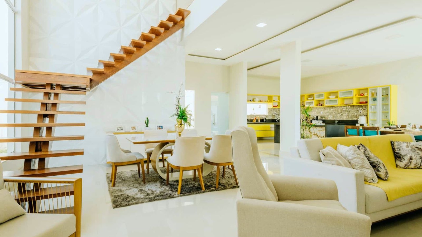 A modern living room featuring bright yellow furniture and a staircase in the background.