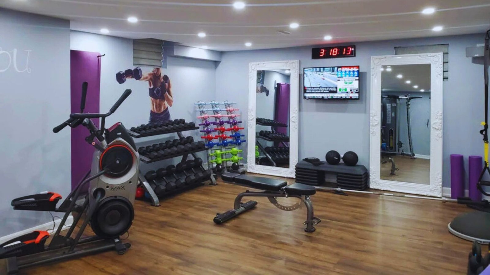 A gym room featuring various exercise equipment and a television mounted on the wall for entertainment during workouts.