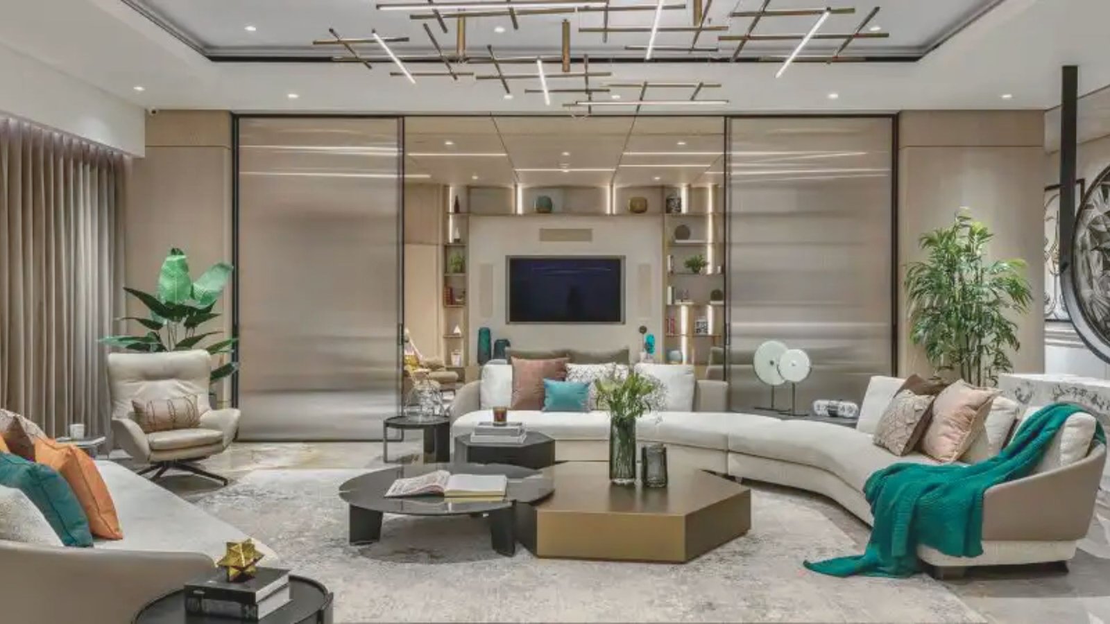 A modern living room featuring a large chandelier hanging from the ceiling, with stylish furniture and decor.